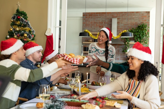 Grupo de amigos felices y diversos celebrando la Navidad en casa