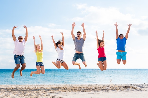 Grupo de amigos felices divirtiéndose juntos en la playa