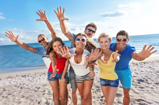 Grupo de amigos felices divirtiéndose juntos en la playa