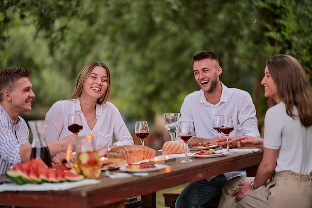 grupo de amigos felices haciendo un picnic en una cena francesa al aire libre durante las vacaciones de verano cerca del río en la hermosa naturaleza