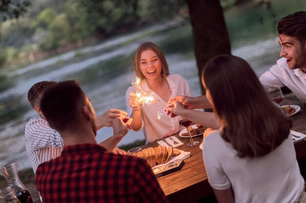 grupo de amigos felices haciendo un picnic en una cena francesa al aire libre durante las vacaciones de verano cerca del río en la hermosa naturaleza