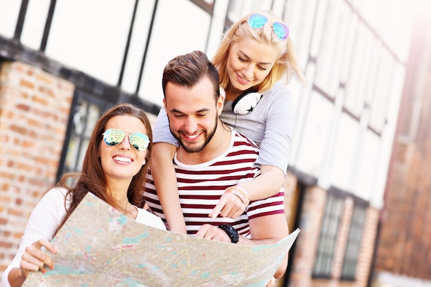 Grupo de amigos felices haciendo turismo en Gdansk con mapa