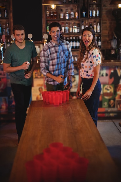 Grupo de amigos felices jugando juego de cerveza pong