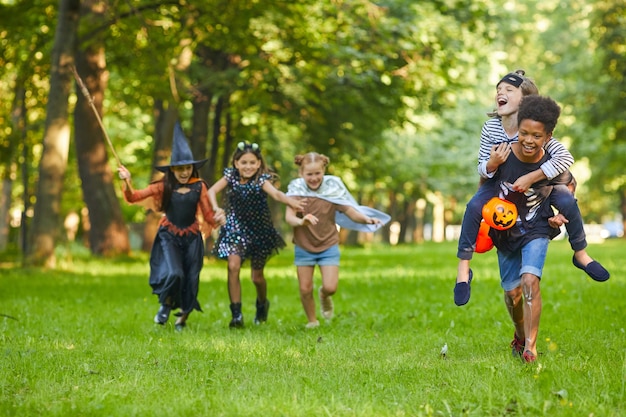 Grupo de amigos felices jugando juntos en el parque durante la fiesta de Halloween