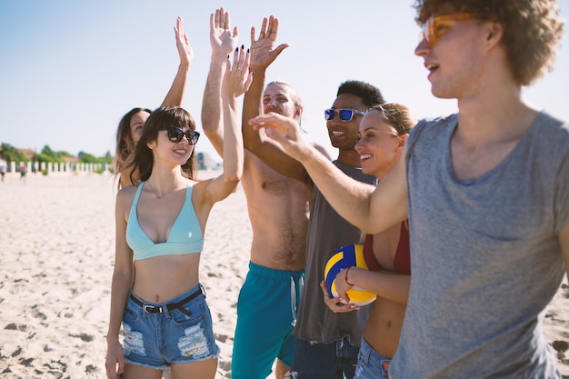 Grupo de amigos felices jugando voleibol de playa en la playa