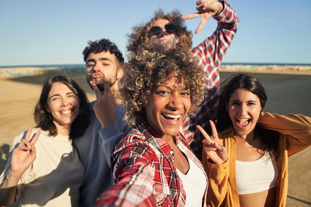 Grupo de amigos felices multirraciales tomando selfie y divirtiéndose juntos