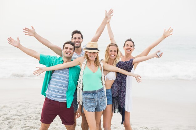 Grupo de amigos felices de pie en la playa