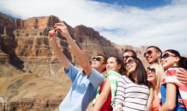 grupo de amigos felices tomando selfie por teléfono celular