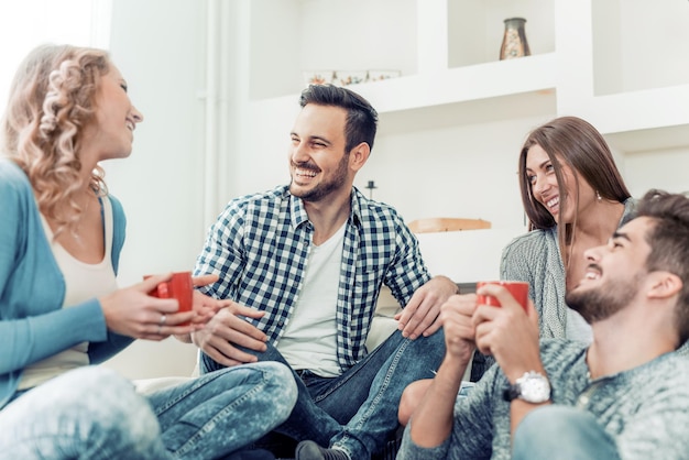 Grupo de amigos hablando y divirtiéndose sentados en el sofá