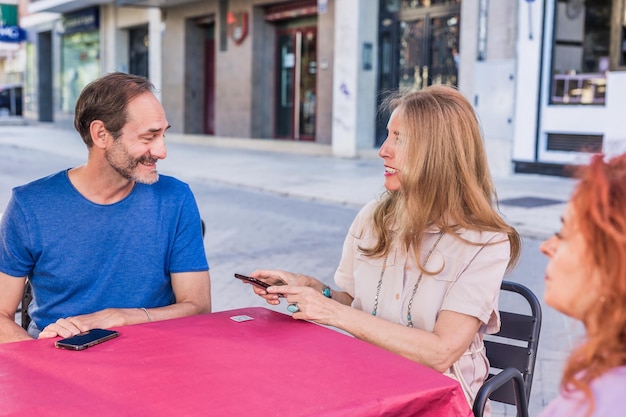 Grupo de amigos hispanos de la diversidad de personas mayores que piden comida con tecnología móvil en un restaurante