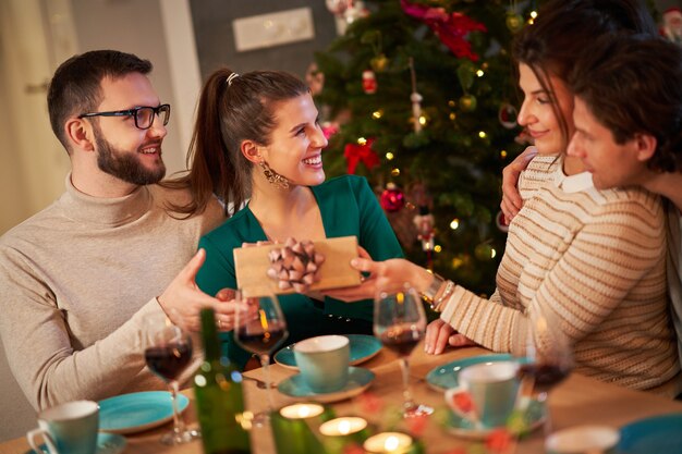 Grupo de amigos intercambiando regalos de Navidad en casa