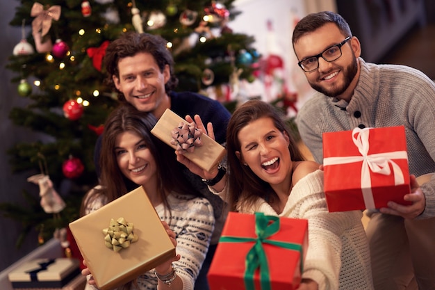 Grupo de amigos intercambiando regalos de Navidad en casa