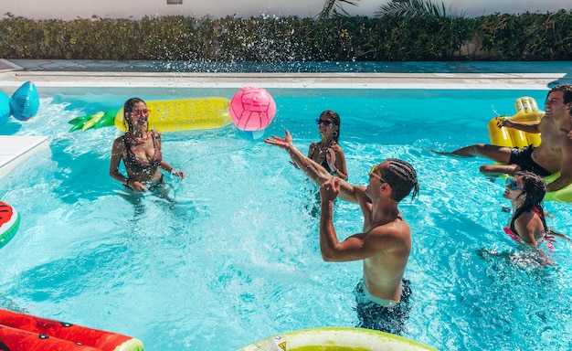 Grupo de amigos juegan juntos en la piscina