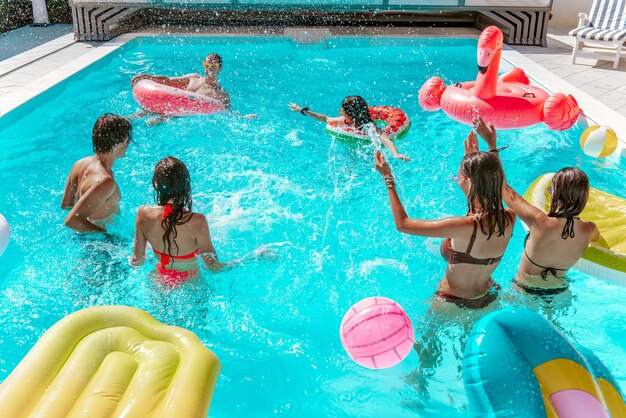 Grupo de amigos juegan juntos en la piscina