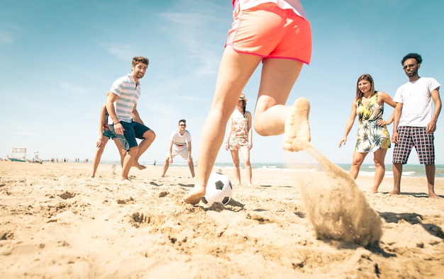 Grupo de amigos jugando al fútbol en la playa