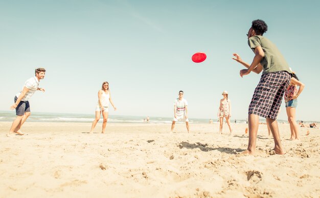 Grupo de amigos jugando con frisbee en la playa