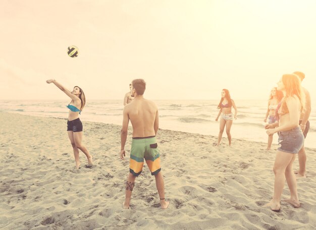 Grupo de amigos jugando con la pelota en la playa