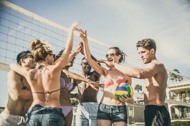 Grupo de amigos jugando voleibol de playa en la playa.