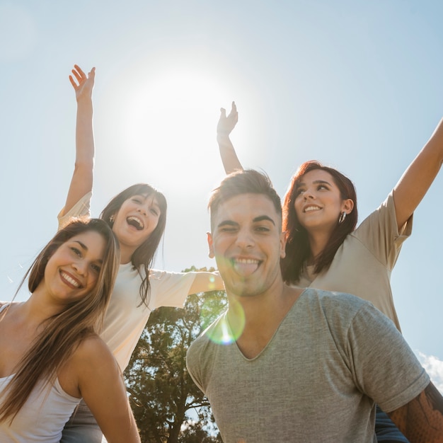 Foto grupo de amigos levantando brazos sobre fondo de cielo