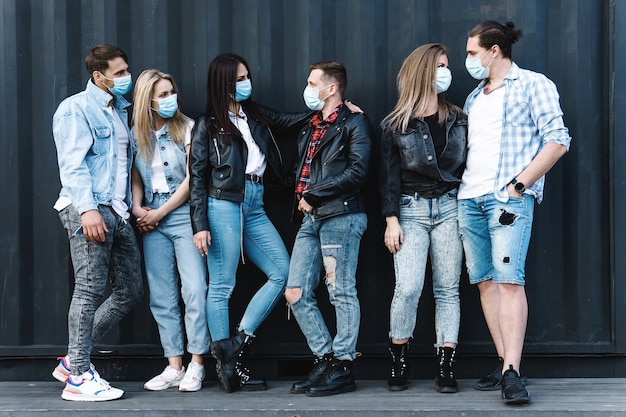 Grupo de amigos con máscaras de prevención durante una reunión en la calle
