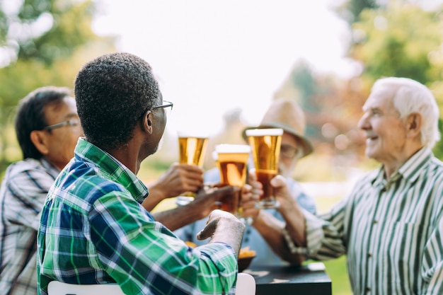 Grupo de amigos mayores bebiendo una cerveza en el parque. Conceptos de estilo de vida sobre la antigüedad y la tercera edad