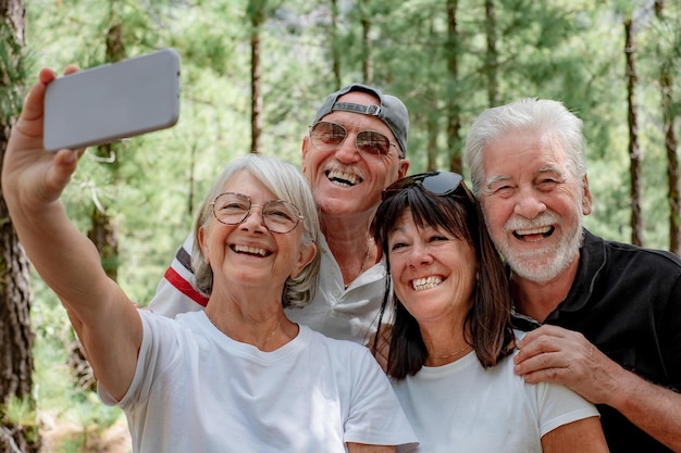 Foto grupo de amigos mayores disfrutando del día de caminata en el bosque hombres y mujeres mayores toman selfie con el teléfono