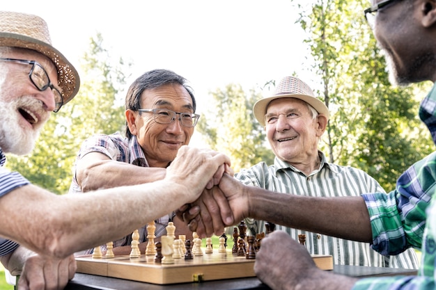 Grupo de amigos mayores jugando al ajedrez en el parque. Conceptos de estilo de vida sobre la antigüedad y la tercera edad