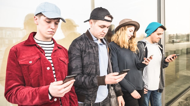 Grupo de amigos multiculturales usando un teléfono inteligente en la universidad