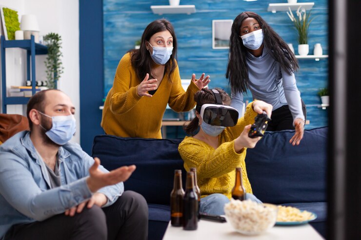 Foto grupo de amigos multiétnicos que se divierten jugando videojuegos con auriculares de realidad virtual y joystick con mascarilla que mantienen el distanciamiento social para evitar la propagación del coronavirus. imagen conceptual.