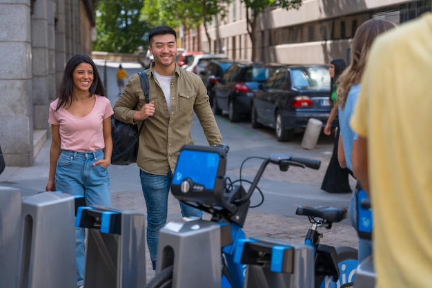 Grupo de amigos multiétnicos en la reunión de la ciudad a la hora de la reunión junto a bicicletas de alquiler