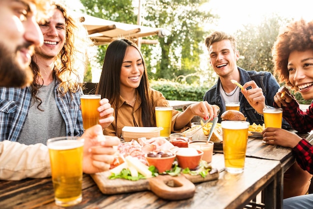 Grupo de amigos multirraciales cenando juntos en el patio trasero