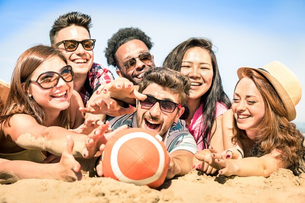 Grupo de amigos multirraciales felices divirtiéndose en juegos de playa