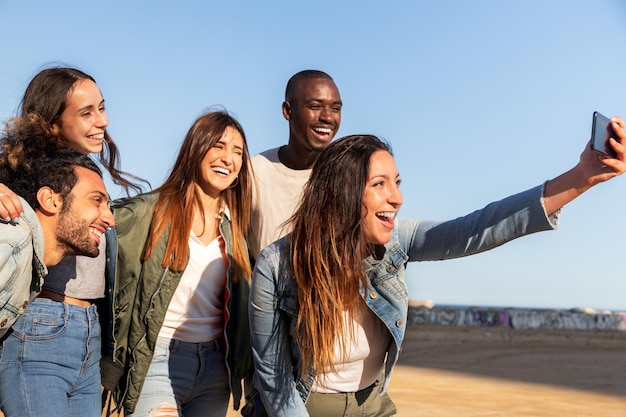 Grupo de amigos multirraciales felices tomando selfie juntos usando teléfono móvil Amigos divirtiéndose