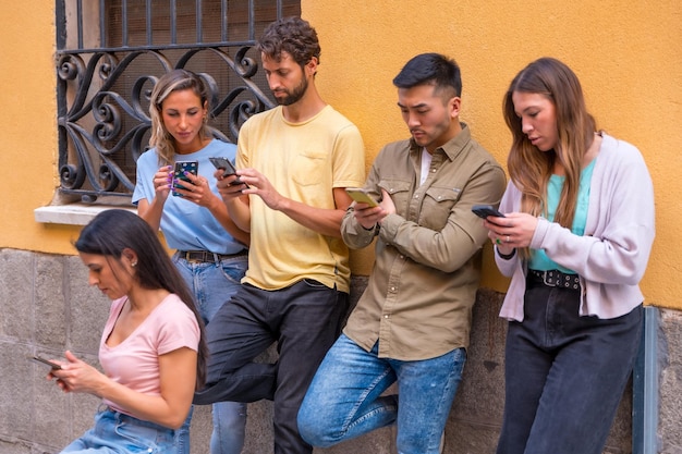 Grupo de amigos multirraciales mirando seriamente el teléfono en el concepto de la ciudad de jóvenes enganchados al móvil