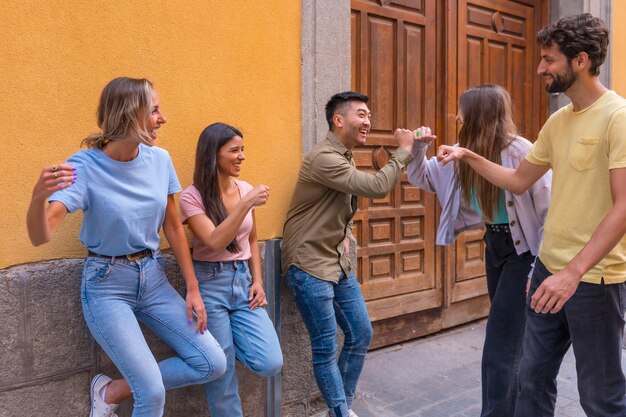 Grupo de amigos multirraciales saludando en el concepto de amistad de la ciudad con chicos y chicas pasando el rato en la calle de la ciudad