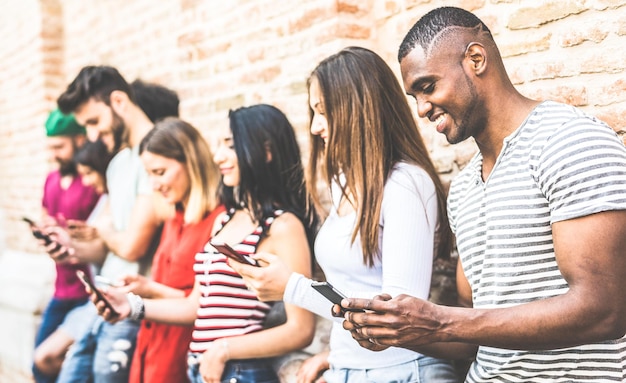 Grupo de amigos multirraciales usando un teléfono inteligente en el descanso de la universidad