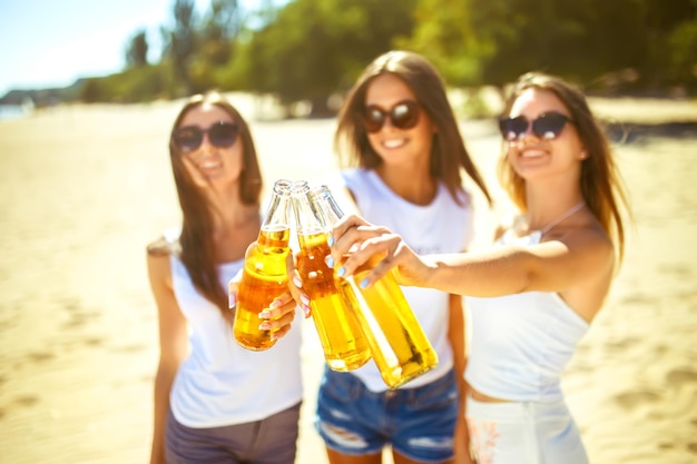 Grupo de amigos pasando el rato con cerveza en la playa Excelente clima soleado Hermosas figuras