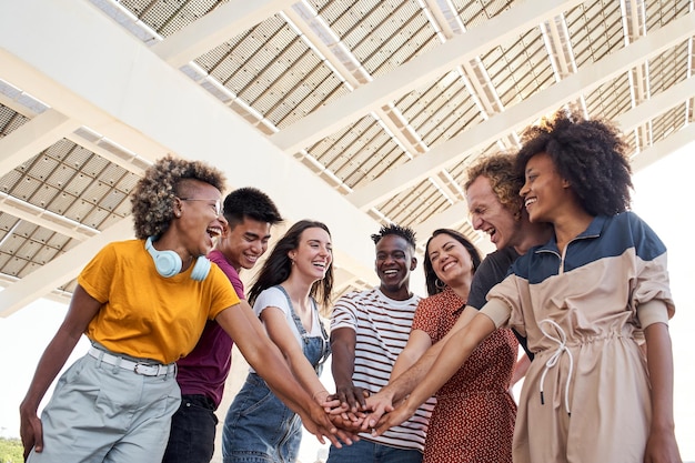 Grupo de amigos que se apilan la mano y son felices de estar juntos personas multiétnicas