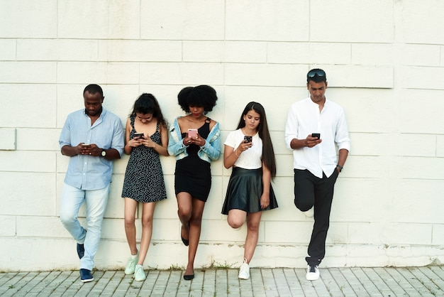 Grupo de amigos riendo por algo que miran smartphone.