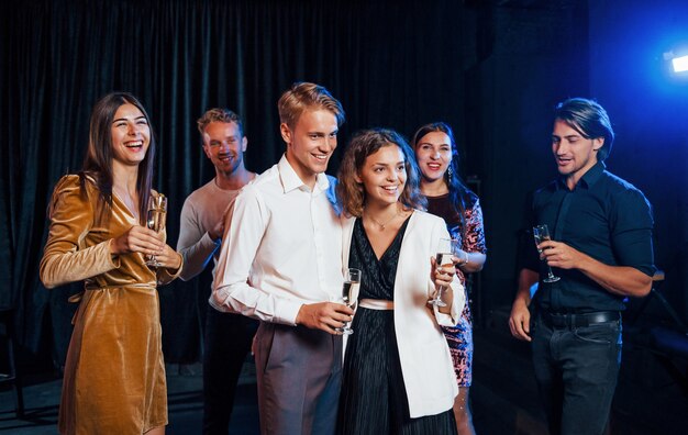 Grupo de amigos en ropa de fiesta tienen fiesta en el interior juntos.