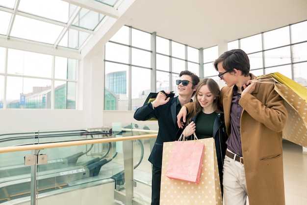 Grupo de amigos sentados al aire libre con bolsas de compras