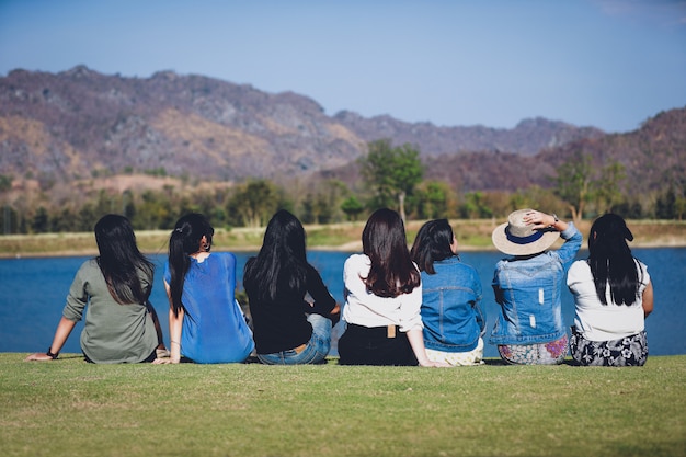 Grupo de amigos sentados felices juntos cerca del lago