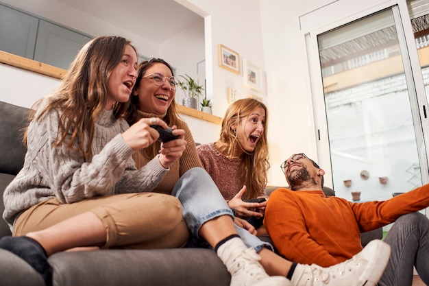 Grupo de amigos sentados en el sofá en la sala de estar y jugar videojuegos en casa