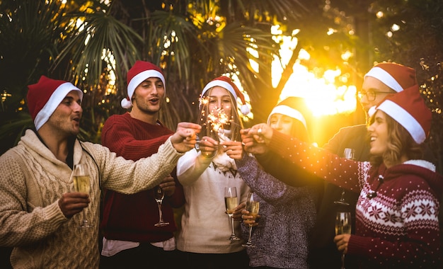 Foto grupo de amigos con sombreros de santa celebrando la navidad con brindis con champán al aire libre