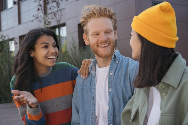 Grupo de amigos sonrientes multirraciales reunidos hablando en la calle Retrato de diversos estudiantes