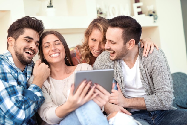 Grupo de amigos sonrientes tomando selfie con teléfono móvil.