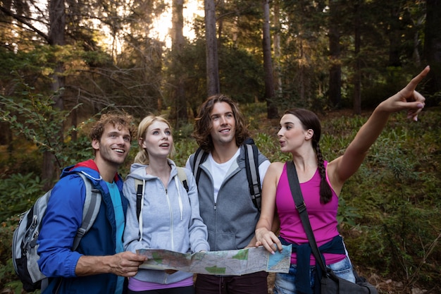 Grupo de amigos sosteniendo un mapa y mirando hacia adelante mientras camina