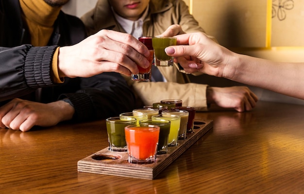 Un grupo de amigos tintinean vasos con tinturas en la mesa Foto horizontal