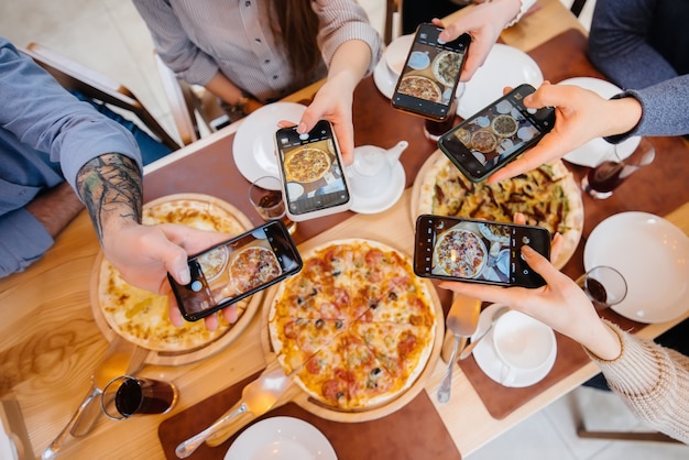 Un grupo de amigos toma una foto en primer plano de una deliciosa pizza para la pizzería del blog