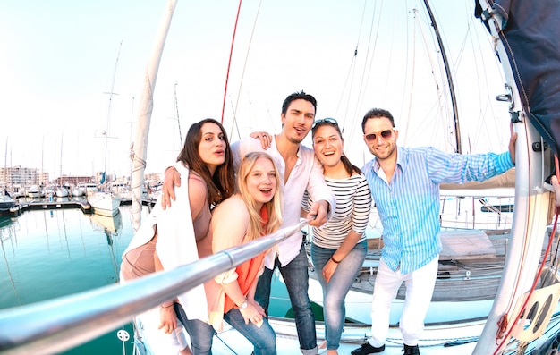 Grupo de amigos tomando foto selfie con palo en un lujoso viaje de fiesta en velero